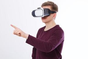 Young Man wearing virtual reality goggles and toch space by finger isolated on white background. VR concept and copy space. Selective focus. Blank template Shirt. photo