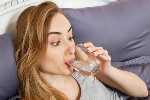 Girl woman drink water in bed at home, healthcare concept, hangover photo