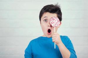 Portrait of child covering eye with lollipop photo