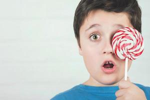 Portrait of child covering eye with lollipop