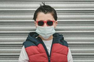 kid wearing medical mask for coronavirus with sunglasses photo