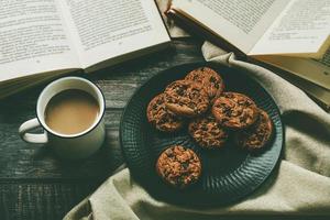 Top view of books with cup of coffee and chocolate cookies. Selective focus photo