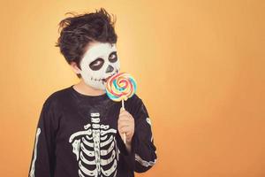 feliz halloween niño divertido en un disfraz de esqueleto comiendo piruleta en halloween foto