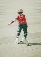 niño patinando con casco en la calle foto