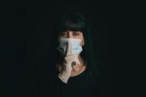 young woman wearing medical mask asking for silence photo