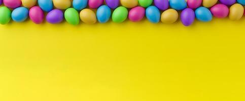 Bunch of colorful eggs on a yellow Easter background 3D Rendering. Pile of birght and colorful Easter Eggs - 3d render. Easter concept composition frame border photo