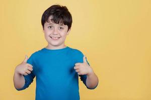 niño pequeño sonriendo mostrando los pulgares hacia arriba foto