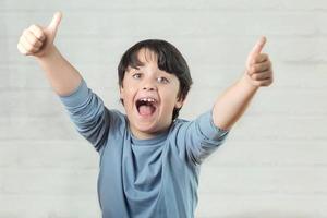 Little boy smiling showing thumbs up photo