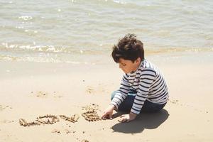 Sad little boy sitting on the beach photo