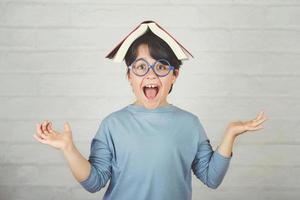 niño feliz y sonriente con el libro en la cabeza foto