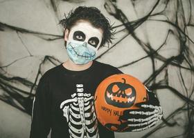 feliz Halloween. niño con máscara médica disfrazado de esqueleto con globo de halloween foto