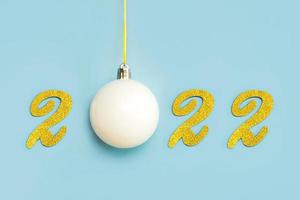 Happy new year 2022. Golden Numbers 2022 and white christmas ball.New Years Eve celebration concept background photo