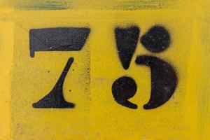 black number 75 stencil painted on yellow background