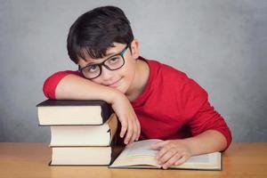 smiling little boy leaning on books on a table photo