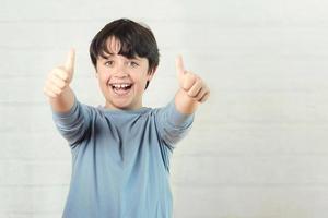 niño pequeño sonriendo mostrando los pulgares hacia arriba foto