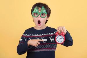 niño sorprendido con reloj despertador con divertidas gafas navideñas foto