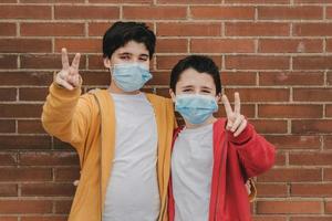 two kids with medical mask doing victory sign photo