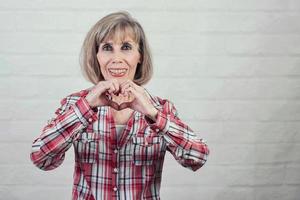 smiling senior woman showing heart with hands photo