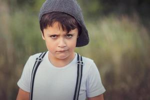 primer plano de un niño enojado con sombrero foto