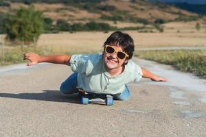 happy kid with skateboard and sunglasses on the road photo