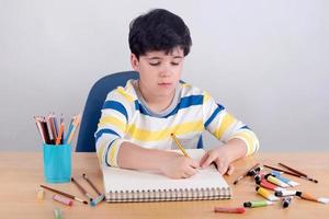 niño dibujando en una mesa foto