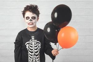 feliz Halloween. niño divertido disfrazado de esqueleto con globos de colores. foto