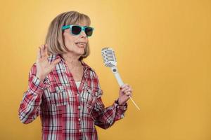 Portrait of Senior woman with sunglasses holding a microphone photo