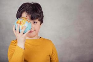 smiling boy with a earth globe covering his eye photo