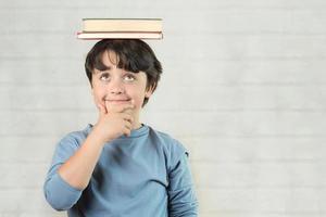 happy and smiling child with books on head photo