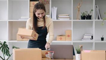 Starting small businesses SME owners female entrepreneurs Use a laptop or notebook to receive and review orders online to prepare to pack boxes, sell to customers, online sme business ideas. photo