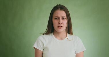 jovem infeliz em t-shirt chora com careta triste desempenhando papel no estúdio com parede verde na audição closeup câmera lenta