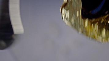 Opening bottle of beer wrapped with golden foil using metal opener on light grey background extreme close view slow motion video