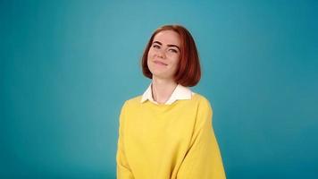 Emotionales junges Frauenmodell im gelben Pullover spricht und lächelt und blickt direkt auf das Vorsprechen der Agentur auf blauer Zeitlupe aus der Nähe video