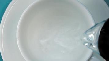 derramando água quente em xícara de porcelana branca com pires em pé na mesa azul vista de perto de cima em câmera lenta video