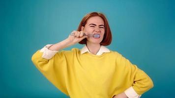 Professional young actress in yellow pullover plays brushing teeth with toothbrush posing for camera slow motion close view