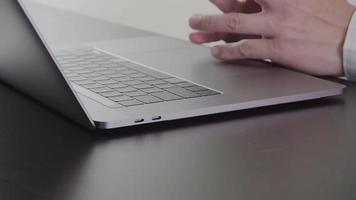 zakenman werken met nieuwe moderne laptopcomputer en bril op houten bureau in slow motion video