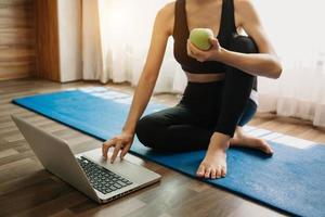 Woman exercising at home and watching training videos with dumbbells and looking at laptop. photo