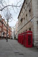 Red british telephone booth in a row on an empty street. London photo