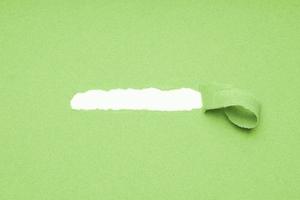 hole torn in green paper background to reveal hidden copy space photo