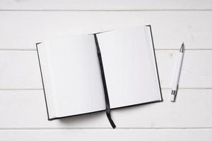 open notebook and pen on white wooden desk photo