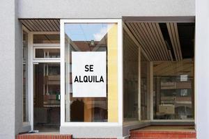 Signo de vacante en español en la ventana de la tienda vacía se lee se alquila significado para alquilar foto