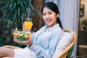 Beautiful young Asian woman enjoying breakfast with salad