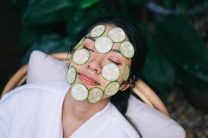 Beautiful young Asian woman wearing cucumber mask photo