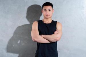 Young Asian personal trainer posing on gray background photo