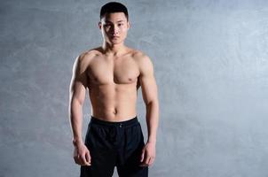 Muscular Asian man posing on gray background photo