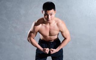 Muscular Asian man posing on gray background photo