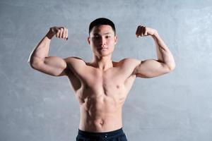 Muscular Asian man posing on gray background photo