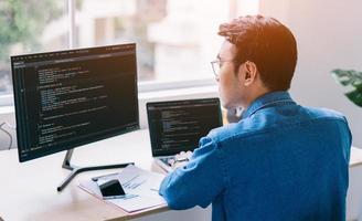 Young Asian programmer working at office photo