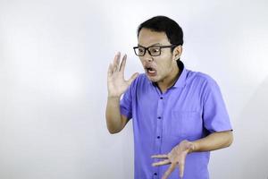 Close up portrait of a young asian man shouting loud and angry facce with arm at his face isolated over white photo
