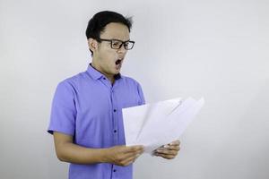 Young Asian man is shocked and surprised with the white mail message or the bill. photo